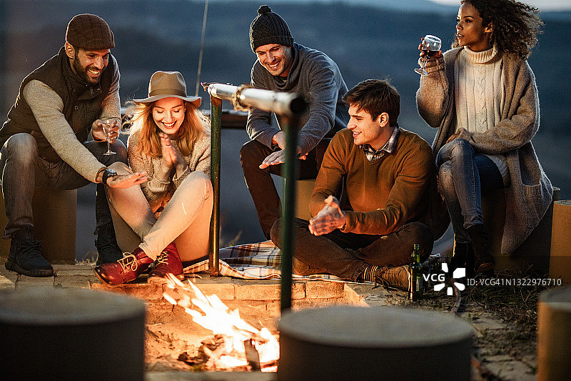 快乐的年轻朋友在秋天的篝火旁享受快乐时光图片素材