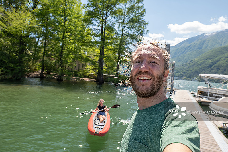 年轻情侣在山地湖泊的红色独木舟上自拍图片素材