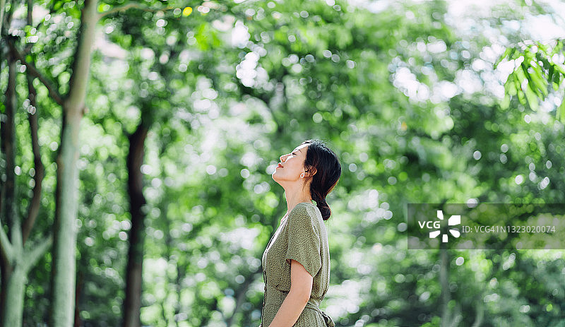 美丽的年轻亚洲女性在大自然中闭着眼睛冥想，放松身心，享受新鲜空气，呼吸平静。与自然联系图片素材