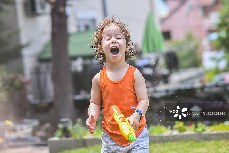 在后院玩水枪的快乐儿童图片素材