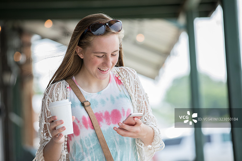 少女发短信，手持咖啡杯图片素材