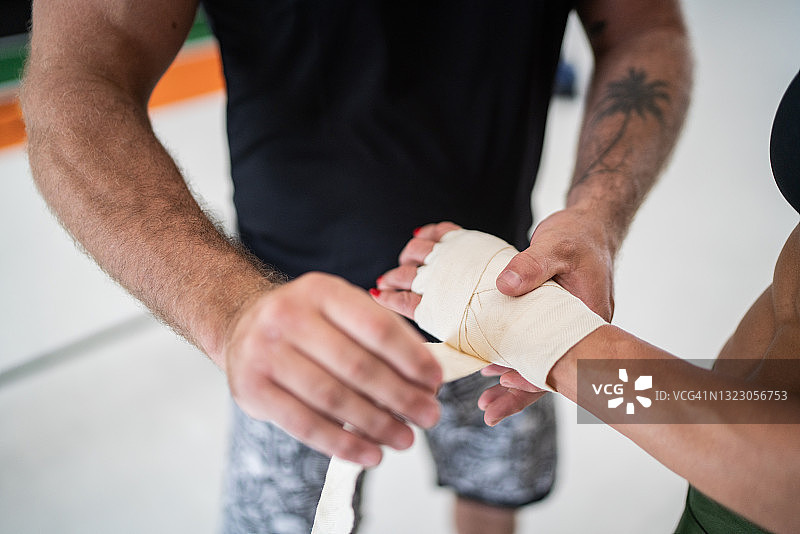 泰拳拳击手在健身房教练的帮助下穿戴护具图片素材