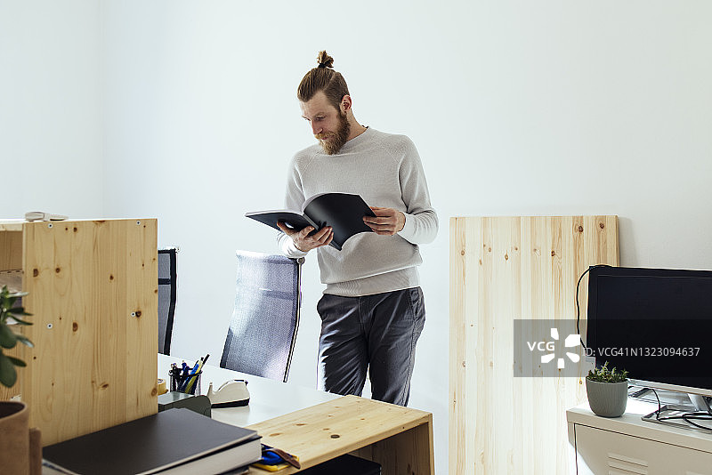 站在办公室里看书的年轻金发商人图片素材