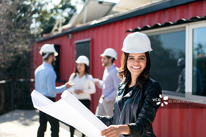 快乐的年轻建筑师拿着图纸对着镜头微笑图片素材