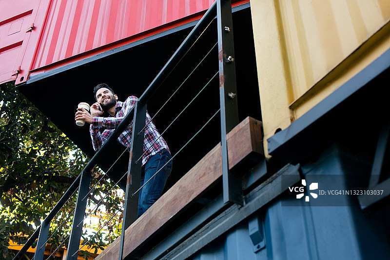 年轻男人在阳台上打电话图片素材