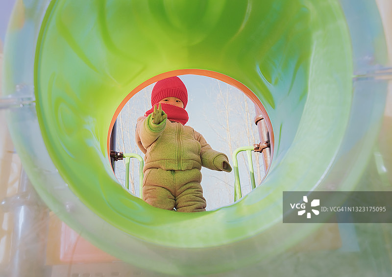 在操场滑梯上玩耍的小男孩图片素材