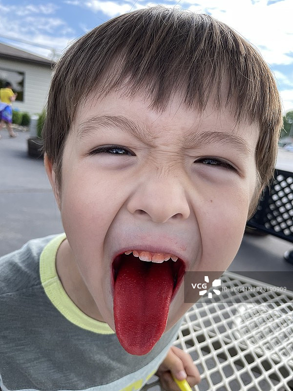 吃了糖果和冰淇淋后，伸出鲜红舌头的学龄男孩图片素材
