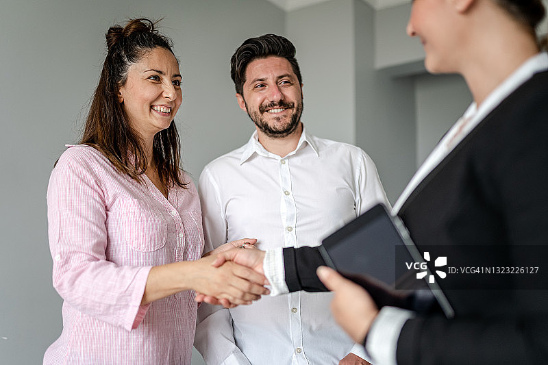 房地产经纪人与家庭握手成交图片素材