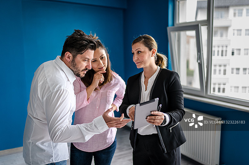 房地产经纪人与年轻夫妇洽谈房产交易图片素材