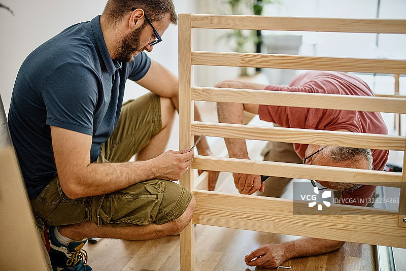 父亲帮助儿子组装床架图片素材