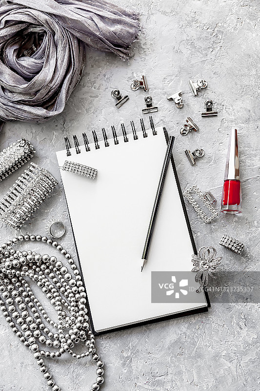 用于模型制作的空白螺旋笔记本、办公用品和女性珠宝俯视图。女性居家办公工作区概念。图片素材