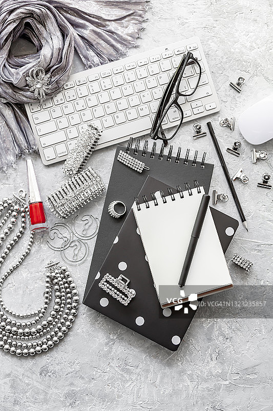 俯视角度的空白螺旋笔记本、电脑键盘鼠标、办公用品、眼镜和女性饰品图片素材