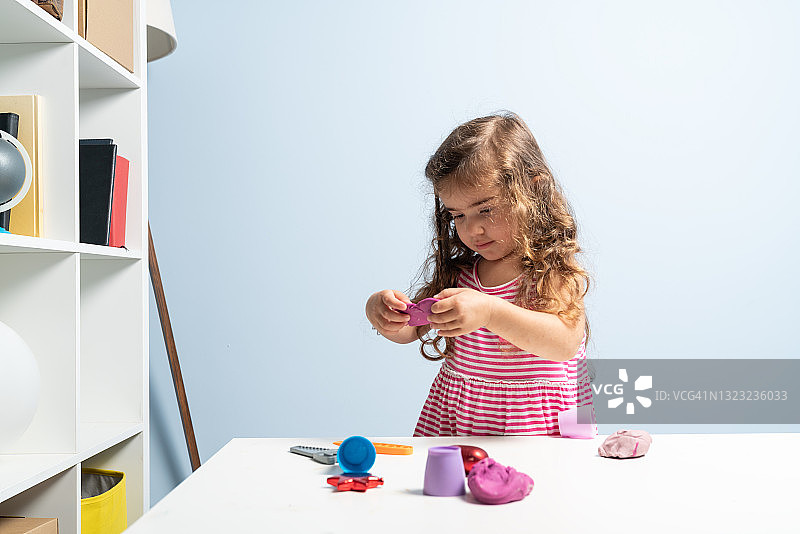 学龄前女孩在家玩橡皮泥照片图片素材