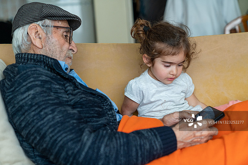 曾祖父和曾孙女使用智能手机图片素材