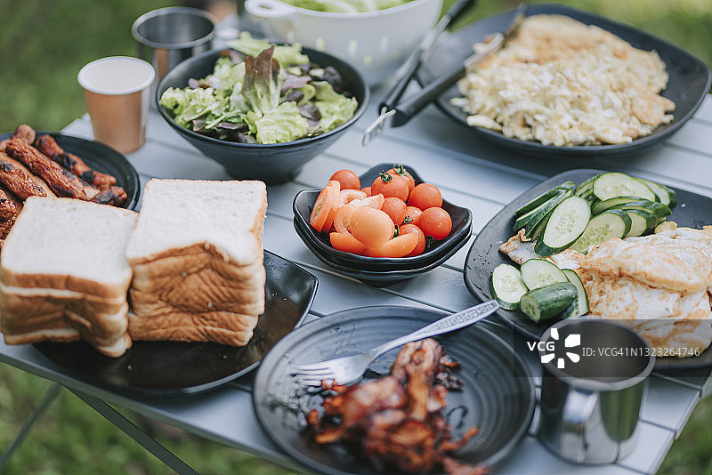 露营帐篷内的健康早餐：面包、香肠、沙拉、鸡蛋、咖啡、培根图片素材