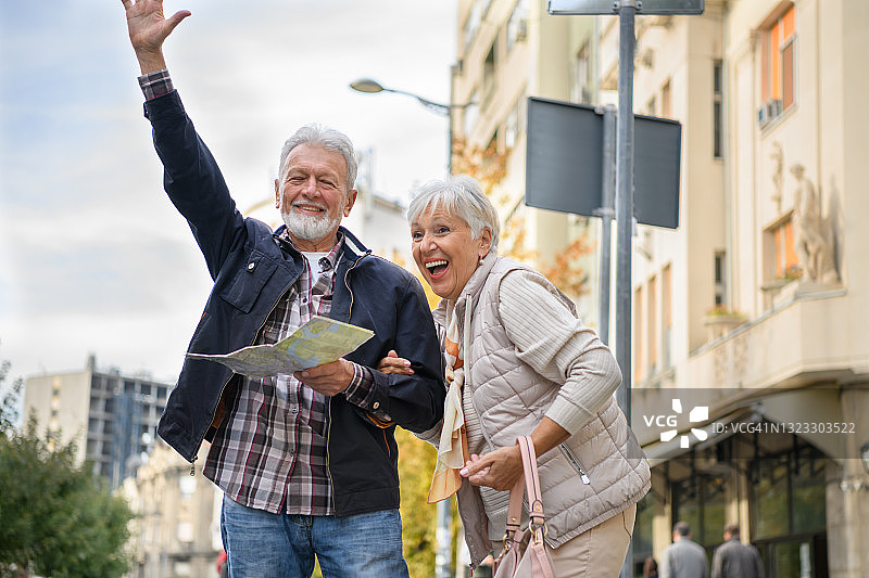 老夫妇站在城市街道旁，试图搭车。图片素材