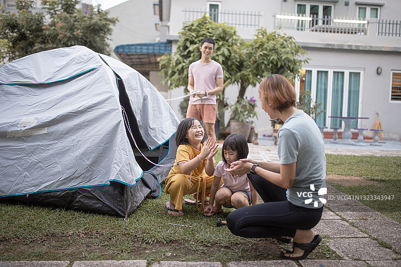 中国兄妹帮助父母在后院搭建帐篷露营图片素材