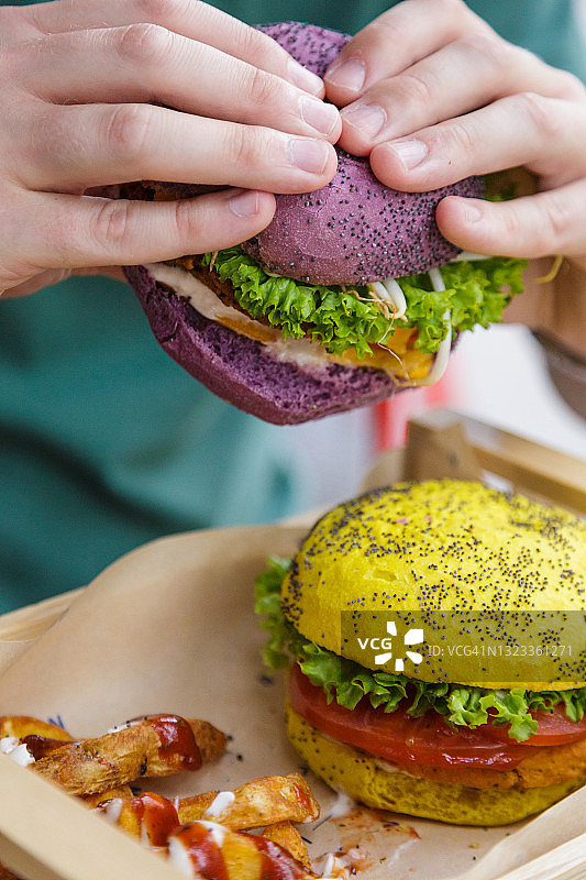 男子手持彩色面包里的纯素汉堡图片素材