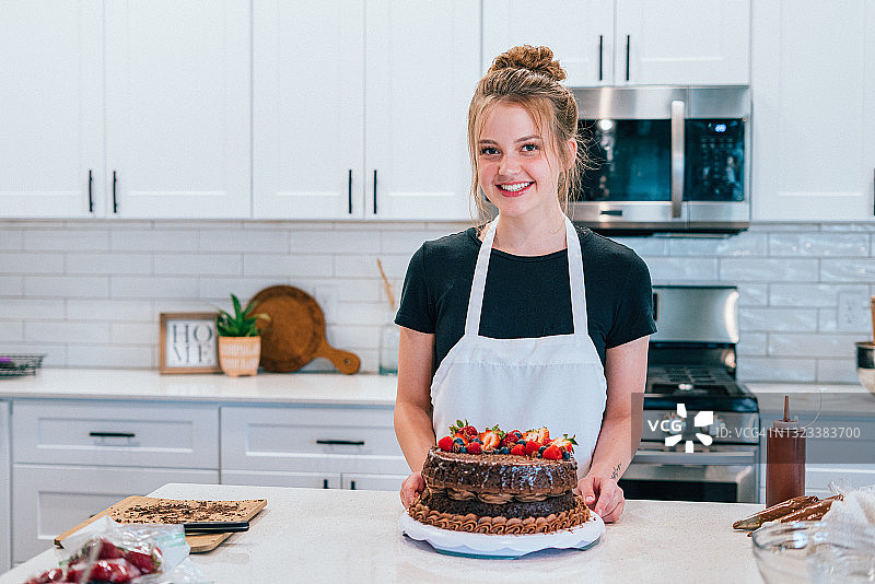 在家自豪地展示美味巧克力蛋糕的年轻女人图片素材