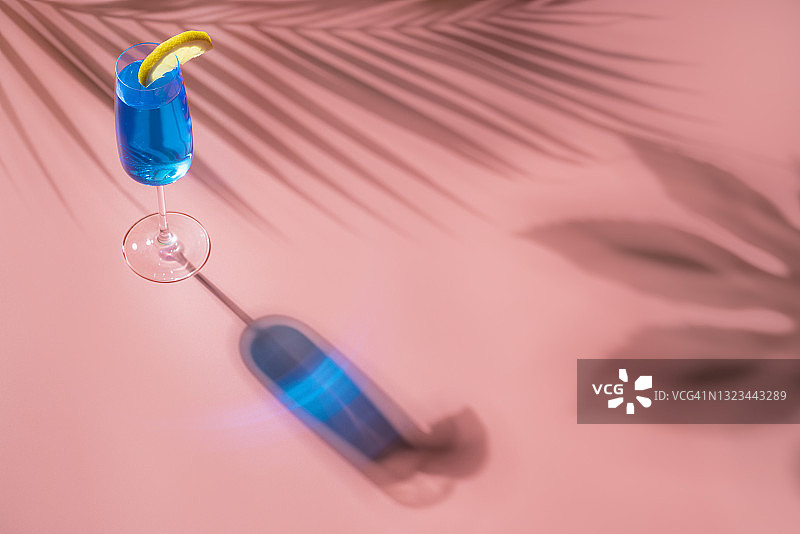 粉色背景下带有硬光和阴影的蓝色无酒精鸡尾酒图片素材