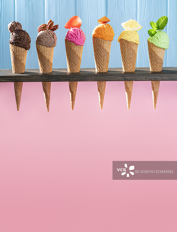 一排什锦冰淇淋蛋卷，粉色和蓝色木纹背景图片素材