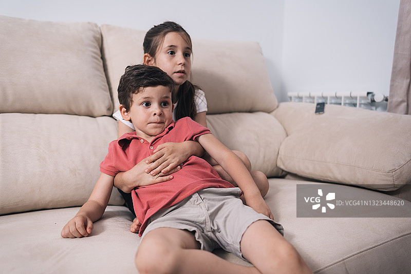 小男孩和姐姐在沙发上看电视图片素材