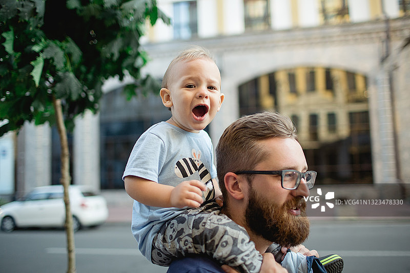 有趣的小男孩趴在他父亲的背上图片素材