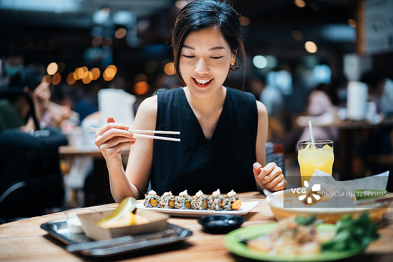 快乐的亚洲年轻女性在美食大厅享用来自世界各地的美味佳肴和各种美食。 国际美食和饮食文化。 外出就餐的生活方式图片素材