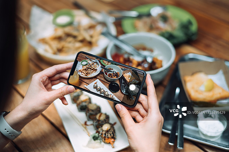 女子在美食广场用手机拍摄美食照片图片素材