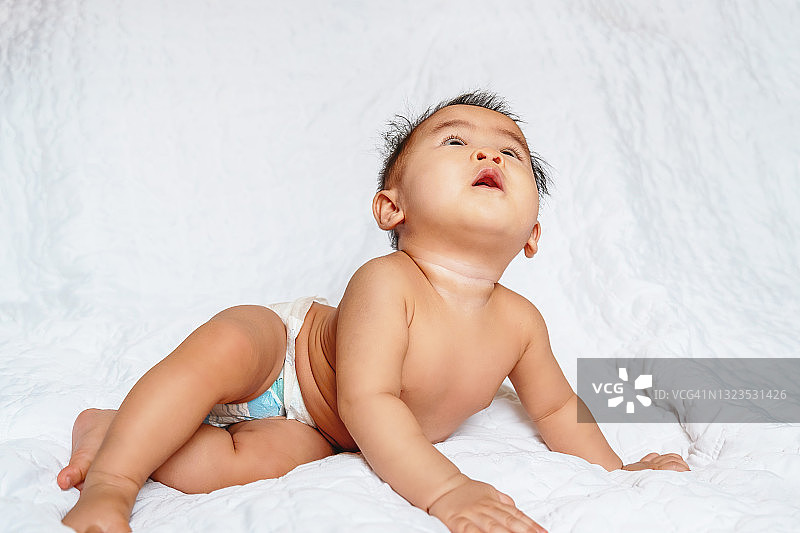 白色背景下抬头看尿布的婴儿图片素材