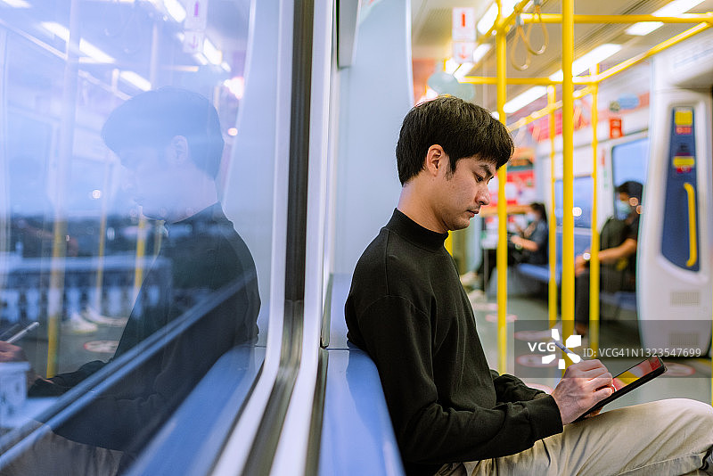 在火车上使用笔记本电脑发信息的亚洲商人图片素材