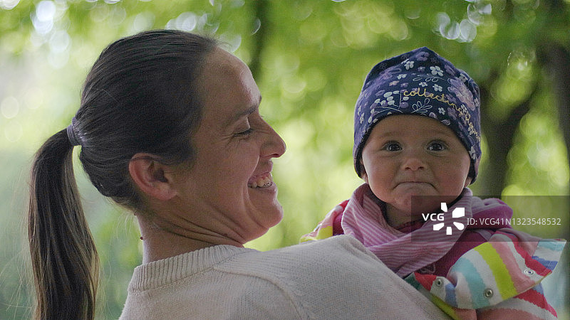 母亲带着宝宝在阳光明媚的榉木林中散步图片素材