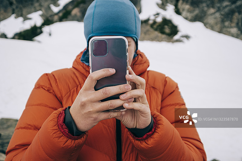 在寒冷山区用手机遮挡的登山者图片素材