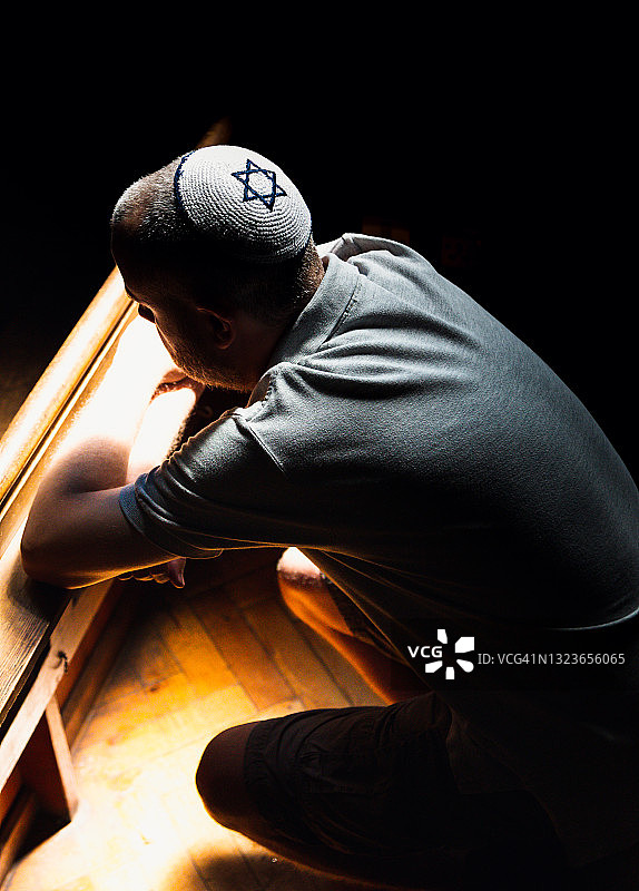 年轻的犹太男子戴着小圆帽在会堂里祈祷图片素材