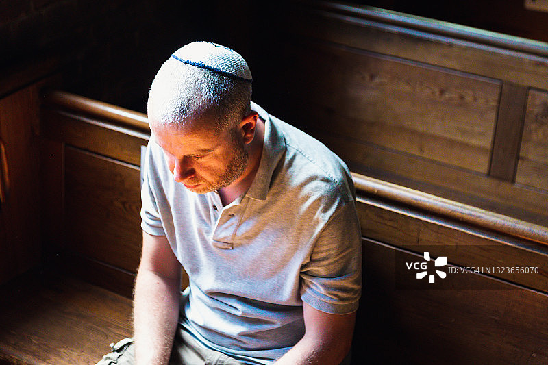 戴着小圆帽在犹太教堂内祈祷的年轻男人图片素材