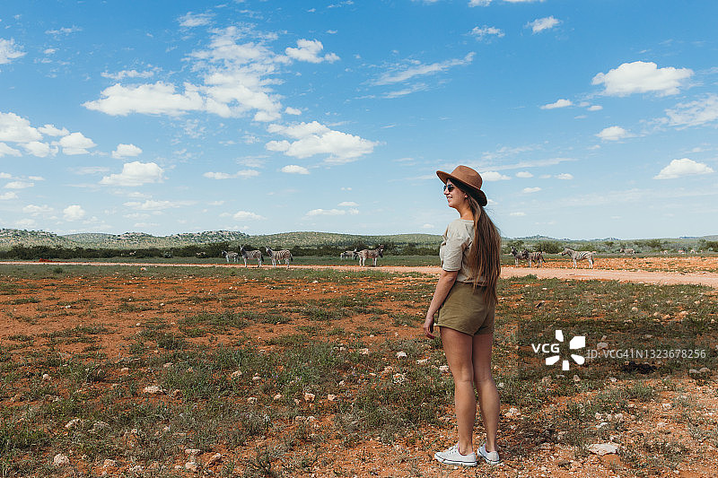 年轻女子在纳米比亚埃托沙国家公园进行狩猎之旅，观看斑马图片素材
