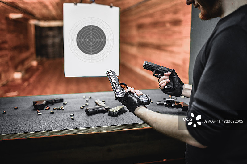 男射击手在靶场上比较不同手枪的重量图片素材