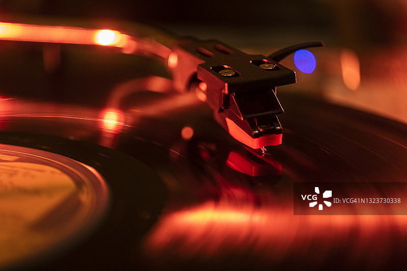 红光下唱片播放机唱针在唱片上的特写图片素材