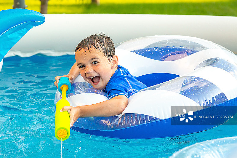 在游泳池里玩水枪的男孩图片素材