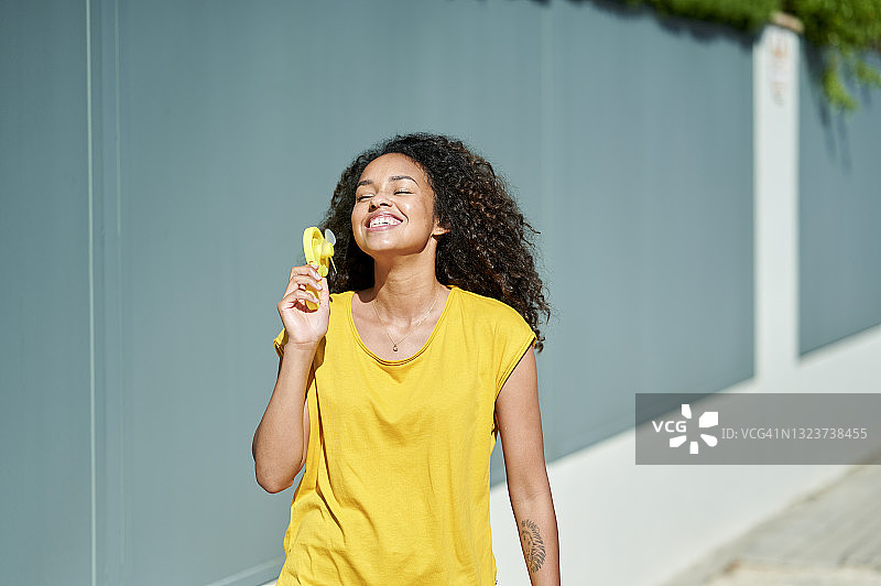 在街上拿着便携式风扇的女人图片素材