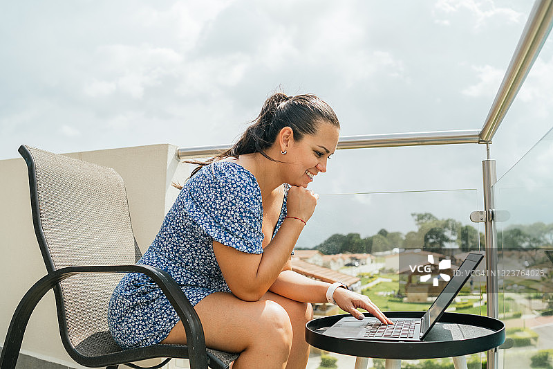 在阳台上使用笔记本电脑的放松女人图片素材