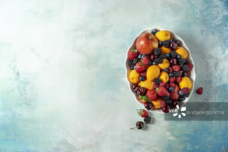 绿松石背景的碗中装着各种新鲜水果图片素材