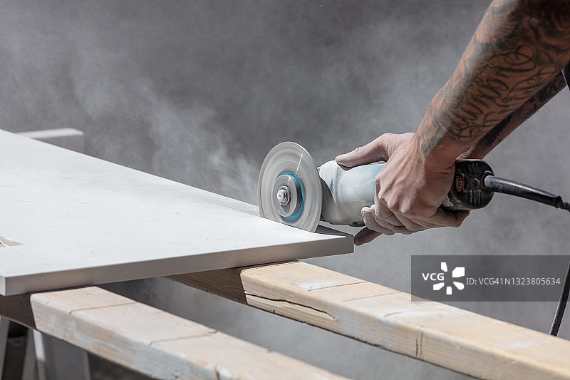 带纹身的男人用锯子切割厨房台面图片素材