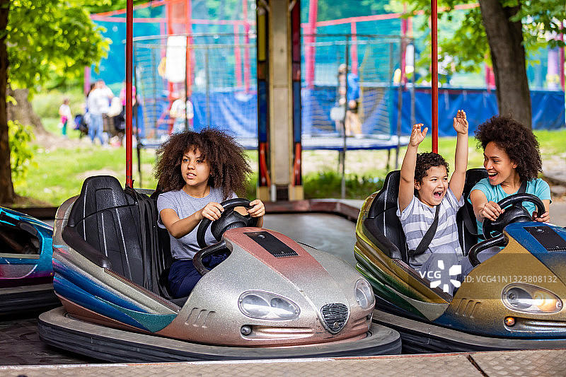 一个非洲裔美国家庭在游乐园里玩碰碰车。图片素材