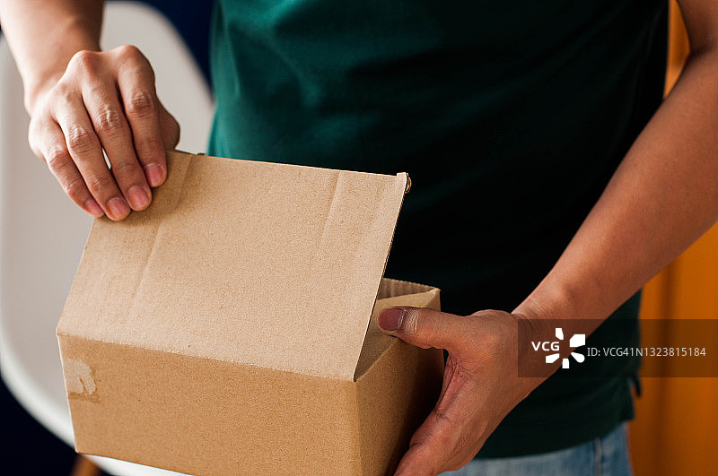 打开纸箱包装的东南亚男子图片素材