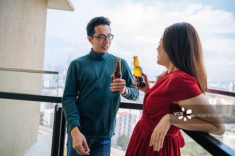在屋顶派对上用啤酒敬酒的年轻亚洲夫妇图片素材