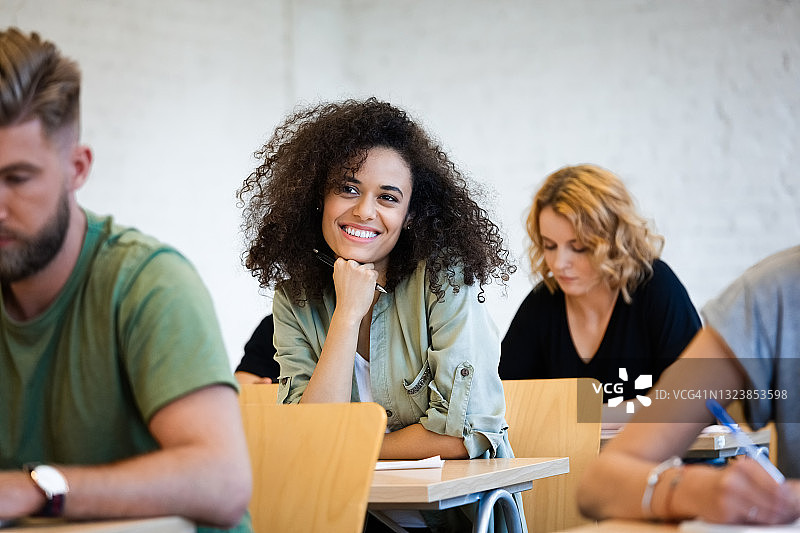 微笑的学生手托下巴坐在桌旁图片素材