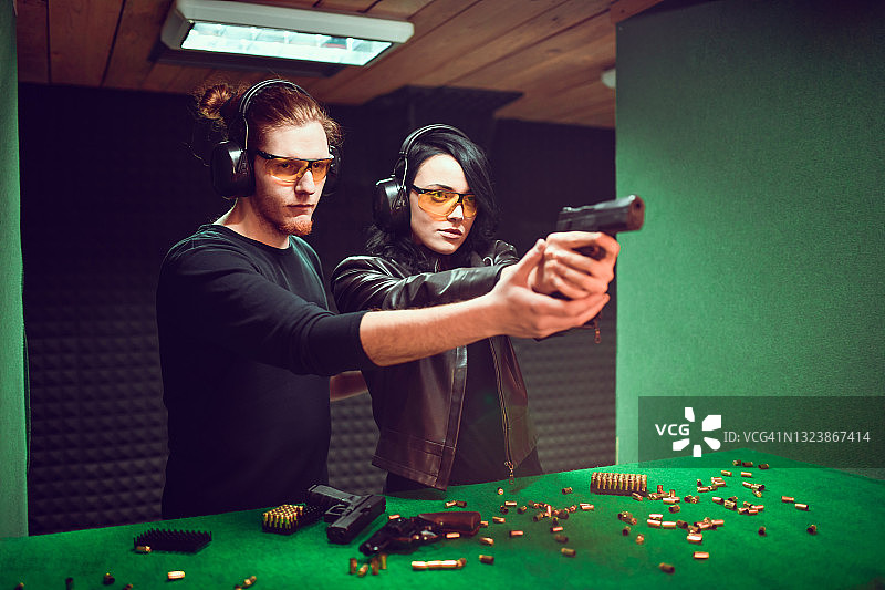 男性射击教练帮助女学员掌握正确的握枪姿势图片素材