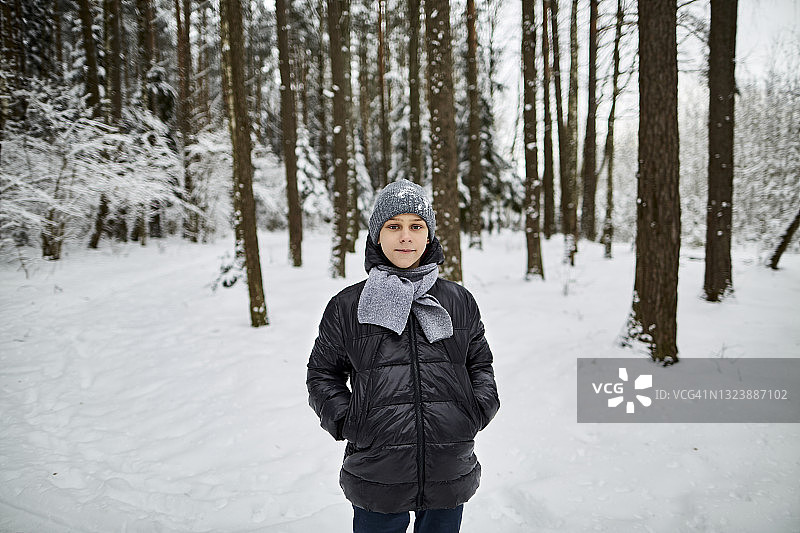 站在冬季森林中的男孩肖像图片素材