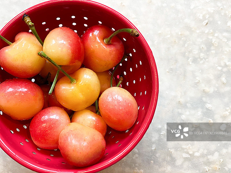 白色背景上的红色金属小漏勺装满新鲜有机樱桃的局部视图图片素材